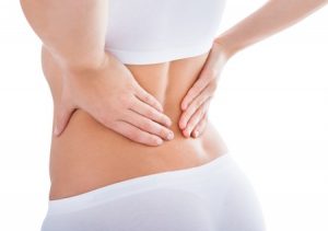 腰が痛くて腰に手を当てる女性の写真
