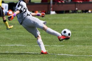 オスグットになり易い成長期のサッカーのゴールキーパーがサッカーボールを蹴る写真