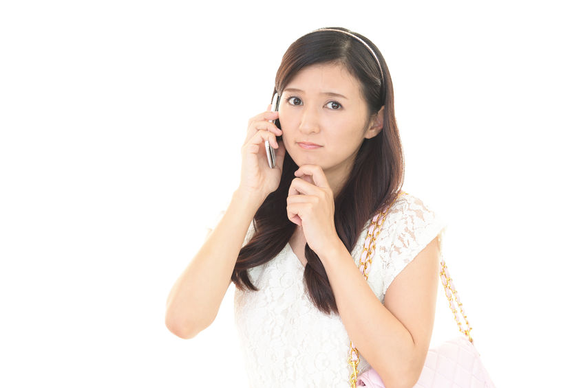 遠絡(えんらく)療法の治療を電話予約する女性の写真